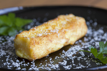 Crocchetta di patate con prezzemolo e formaggio grattato disposta su un piatto nero