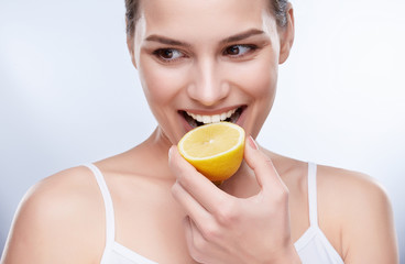 Smiling woman biting lemon
