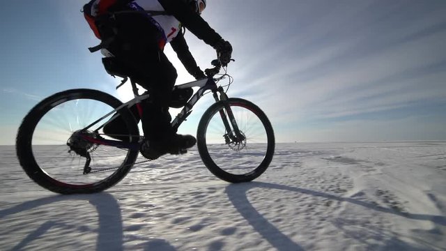 a man riding a bicycle across a frozen lake