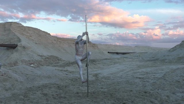 Man climbs a pole in the desert, he shows the show.