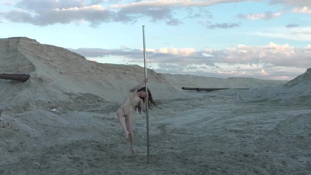 Woman rotates on the pole, he dances and shows the show.