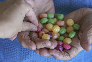 young hand picks a hard candy from palm of an old person