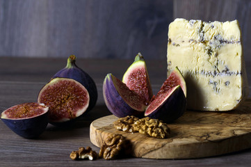 Cheese roquefort with figs and nuts on a wooden background