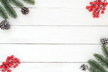 Christmas and New year background with fir branches, holly berry and pine cones on white wooden background.  Creative flat lay, top view design with copy space