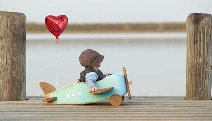 kleiner Junge am See mit Holzflieger