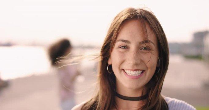 Young brown haired woman with large smile and friends in the background
