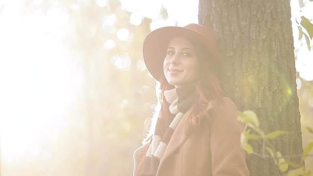 Redhead girl in yellow hat and coat with scarf on autumn park