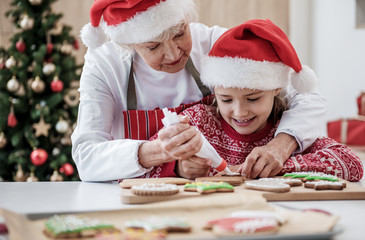 Happy granny applying cream on holiday pastry