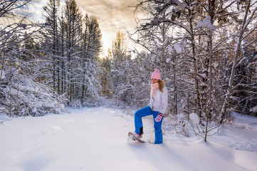 Winter sport activity. Woman with snowshoes on fluffy snow in forest. Beautiful landscape with...