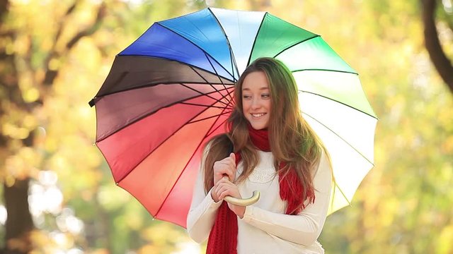 Young girl with colorful umbrella at park.