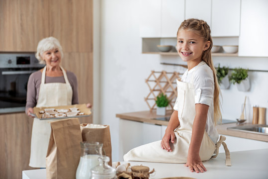 Joyful old woman treating her granddaughter by sweet pastry