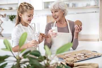 Excited child tasting self-made cookies with granny