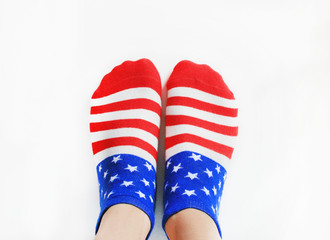 Person Wearing Socks with American Flag. Pair of cotton socks in red, blue and white color, United States flag pattern. Women and men fashion accessory isolated on white empty background copy space