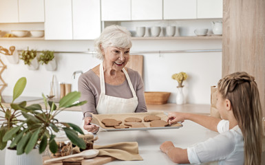 Cheerful old woman giving sweets to her grandchild
