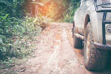 4x4 offroad Wheel closeup in a countryside landscape into a forest with a muddy road © doidam10