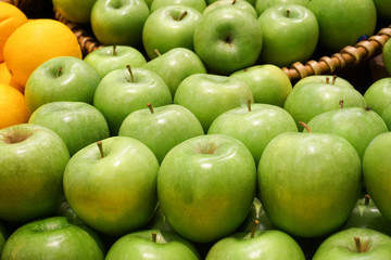 Variety of organic apples in baskets on wood table.