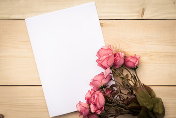 Top view of Creative writing concept with notepad and pink rose on wood background. Copy space for text. Blank area for text or message.Vintage or retro tone.