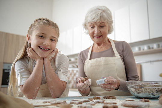 Carefree child enjoying cooking with her grandmother