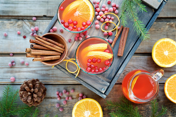 Warm cranberry drink with oranges and cinnamon. Wooden background, top view 
