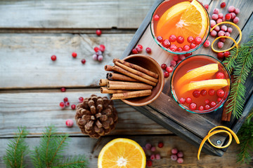 Warm cranberry drink with oranges and cinnamon. Wooden background, top view 
