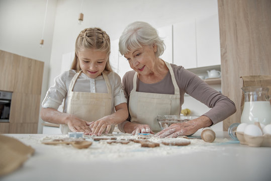 Cheerful girl and granny making shape of dough
