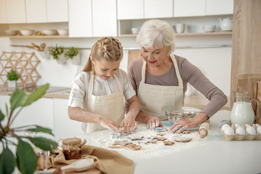 Happy grandmother teaching kid to bake