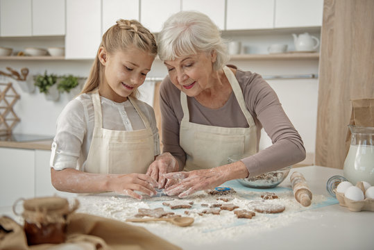 Cheerful grandchild learning to make pastry in kitchen