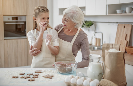 Happy kid learning to bake pastry with her grandmother