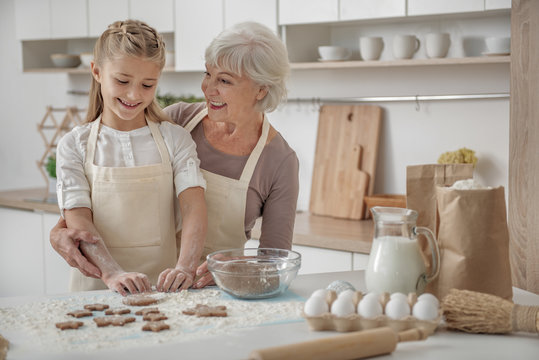 Cheerful grandmother teaching child to cook