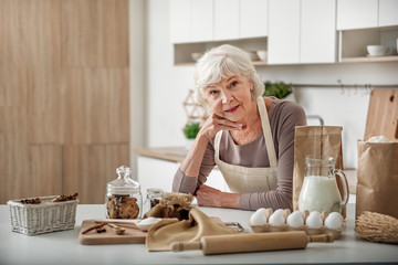 Happy mature lady preparing pastry at home