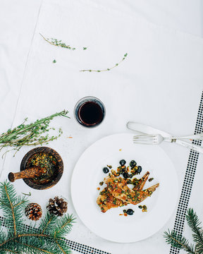 Rabbit with olives, herbs and pine nuts on white tablecloth