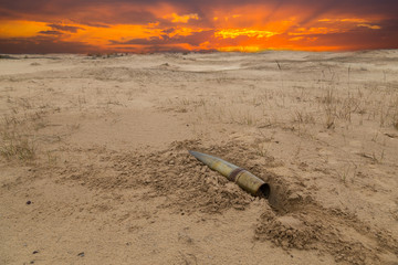 old artillery metal projectile on the sand in the desert