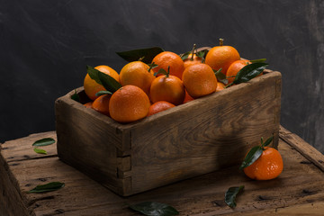 Fresh tangerines with leaves in an old wooden box - obrazy, fototapety, plakaty