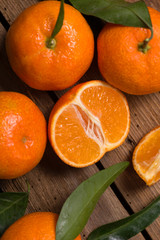 Fresh clementines with leaves on wooden table close up