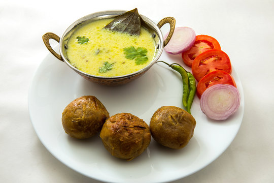 Tradtional Rajsthani food Kadi Bati or Dal Bati served with salads - tomato, onion and green chilli