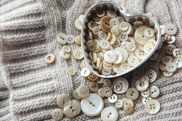 Close-up of heart shaped container with pearl buttons