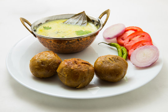 Tradtional Rajsthani food Kadi Bati or Dal Bati served with salads - tomato, onion and green chilli