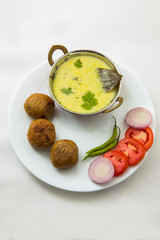 Tradtional Rajsthani food Kadi Bati or Dal Bati served with salads - tomato, onion and green chilli