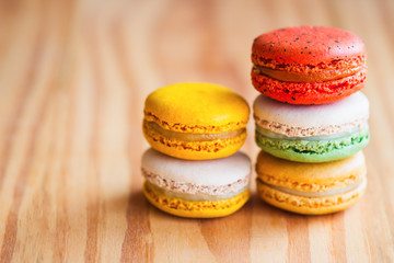Fototapeta na wymiar Close up colorful French macaron or Italian macaron. Homemade delicious macaron stack on wood table with copy space for background or wallpaper macro concept. French dessert served with tea or coffee.