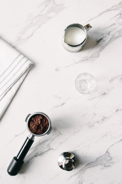 coffee group head with ground coffee, tamper and milk jug