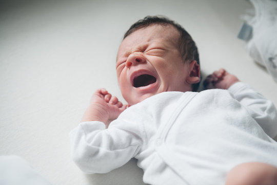 Newborn boy crying in his bed