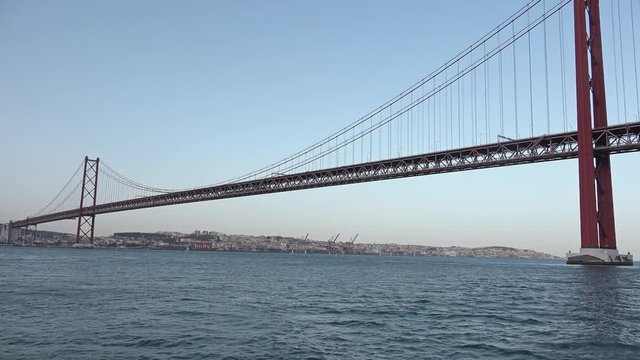 Suspension Bridge In Lisbon Shot From Boat In Tejo River. The 25 de Abril Bridge is a suspension bridge connecting the city of Lisbon to the municipality of Almada.