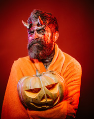 Halloween man devil hold pumpkin on red background
