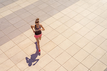 Young fit woman running in sunny day in the city fill active girl.