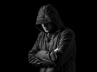 Lonely, depressed and fragile man hiding face, arms crossed and standing in the darkness. Low key, black background. Concept for loneliness, depression, sadness and mental health issues