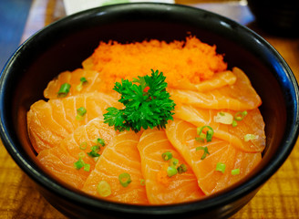 Close up salmon sashimi and  ebiko with rice in black bowl