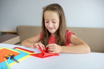 The girl puts origami from paper. Lesson of origami