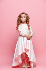 Full length of beautiful little girl in dress standing and posing over white background