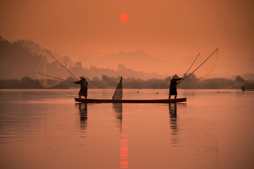 Two fishermen are fishing on the boat at Mekong river in the morning in Nong Khai, Thailand