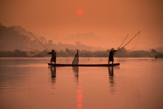 Two fishermen are fishing on the boat at Mekong river in the morning in Nong Khai, Thailand